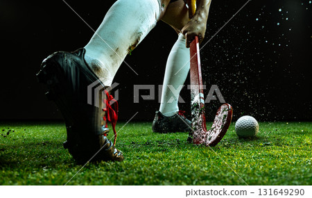 Field hockey player in action during intense match with flying grass particles Field hockey player in action during intense match with flying grass particles 131649290