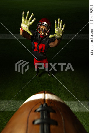 American football player Raising arms to catch the ball on green field under night lights. 131649291