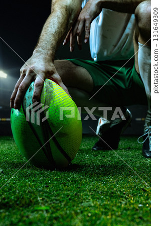 Close-up of rugby player placing green ball on wet grass before match start 131649309