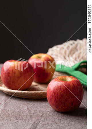 Red apple fruit (Envy apple) in basket on brown fabric with black background 131649351