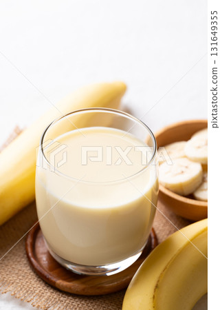 Banana milk in glass with sliced banana and fruit on white background 131649355
