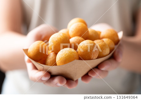 Deep fried sweet potato balls in paper bowl holding by hand, Thai street food  131649364