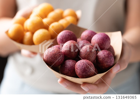 Deep fried sweet potato balls in paper bowl holding by hand, Thai street food 131649365