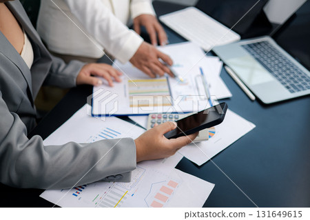 Businesswomen analyzing financial data using smartphone and laptop in modern office 131649615
