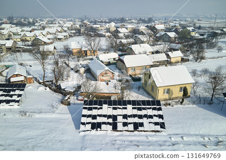 Aerial view of snow melting from covered solar photovoltaic panels installed on house rooftop for producing clean electrical energy. Low effectivity of renewable electricity in nothern region winter Aerial view of snow melting from covered solar photovoltaic panels installed on house rooftop for producing clean electrical energy. Low effectivity of renewable electricity in nothern region winter 131649769