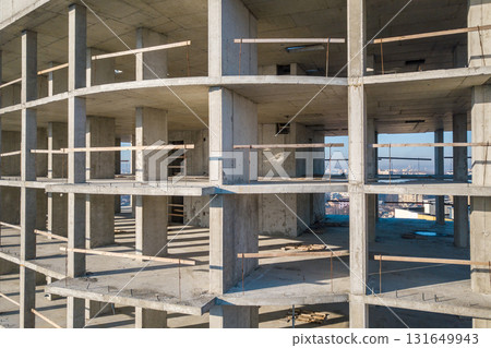 Aerial view of concrete frame of tall apartment building under construction in a city. 131649943