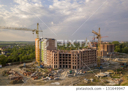 Aerial view of building site. Apartment or office building under construction. Tower cranes on suburb landscape and blue sky copy space background. 131649947