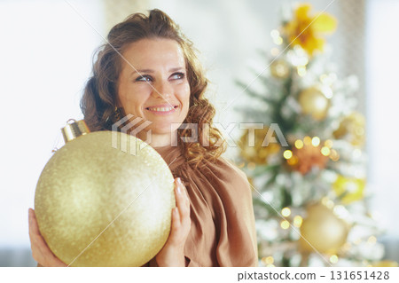 Mid-Adult Woman Smiling With Glittering Gold Ornament Mid-Adult Woman Smiling With Glittering Gold Ornament 131651428