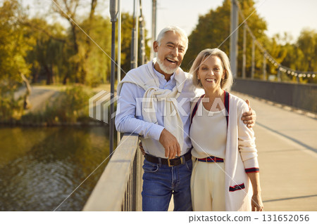 Portrait of happy beautiful mature spouses hugging during walk in summer park. 131652056