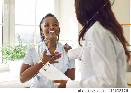 Happy, grateful, young African American woman patient thanking her doctor for help Happy, grateful, young African American woman patient thanking her doctor for help 131652176