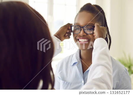 Happy African American female patient trying on glasses as recommended by ophthalmologist. 131652177