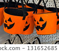 Orange felt buckets with jack o lantern faces and black handles on retail display. Halloween container, candy collection, seasonal festivity, tradition, playful celebration and autumn folklore. 131652685
