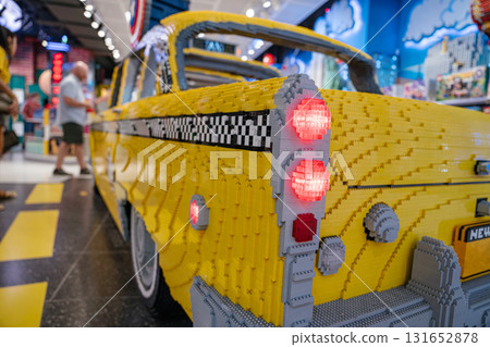 A life-sized model of a classic yellow taxi features detailed brickwork and glowing red taillights. The sculpture captures the nostalgic design of a New York City cab in a colorful toy store setting. A life-sized model of a classic yellow taxi features detailed brickwork and glowing red taillights. The sculpture captures the nostalgic design of a New York City cab in a colorful toy store setting. 131652878