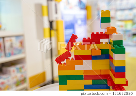 A vibrant structure built from colorful plastic constructor blocks stands on display in a toy store. Bright colors and soft focus in the background create a cheerful and playful atmosphere. A vibrant structure built from colorful plastic constructor blocks stands on display in a toy store. Bright colors and soft focus in the background create a cheerful and playful atmosphere. 131652880