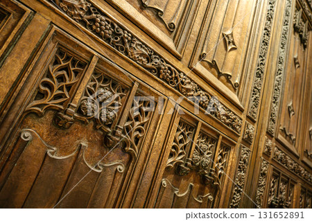 This angled image shows the detailed bronze door of St. Patrick's Cathedral in New York City. Gothic carvings of flowers, vines, and grape clusters decorate the richly textured surface. This angled image shows the detailed bronze door of St. Patrick's Cathedral in New York City. Gothic carvings of flowers, vines, and grape clusters decorate the richly textured surface. 131652891