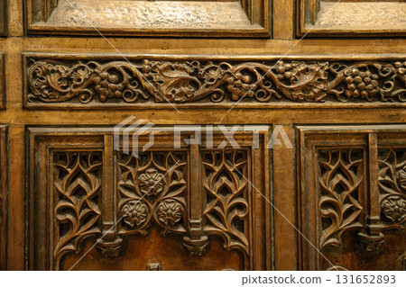 This close-up image shows the detailed bronze carvings on a cathedral door at St. Patrick's Cathedral in New York City. The ornate design includes floral motifs and grapevine patterns in Gothic style. This close-up image shows the detailed bronze carvings on a cathedral door at St. Patrick's Cathedral in New York City. The ornate design includes floral motifs and grapevine patterns in Gothic style. 131652893