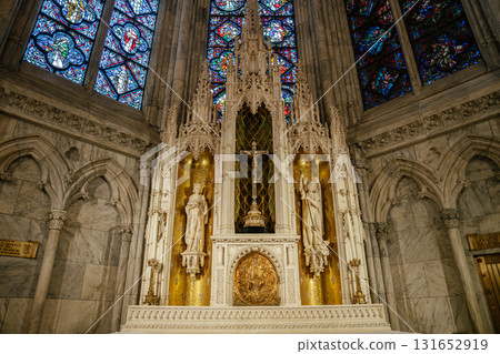 This image showcases a golden Gothic-style altar featuring religious statues, a central crucifix, and shimmering gold mosaic panels. Surrounding stained-glass windows and marble arches enhance the This image showcases a golden Gothic-style altar featuring religious statues, a central crucifix, and shimmering gold mosaic panels. Surrounding stained-glass windows and marble arches enhance the 131652919