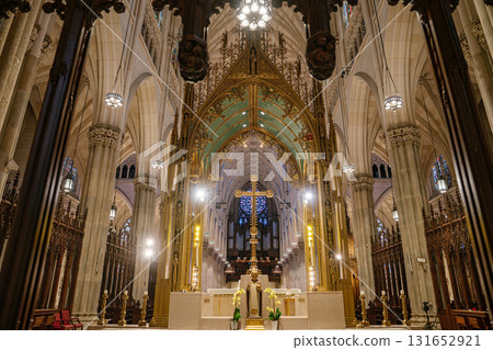 This image features the golden cross and main altar at the heart of St. Patrick's Cathedral in New York City. Surrounded by soaring columns, ribbed arches, stained glass, and elegant lighting, the This image features the golden cross and main altar at the heart of St. Patrick's Cathedral in New York City. Surrounded by soaring columns, ribbed arches, stained glass, and elegant lighting, the 131652921