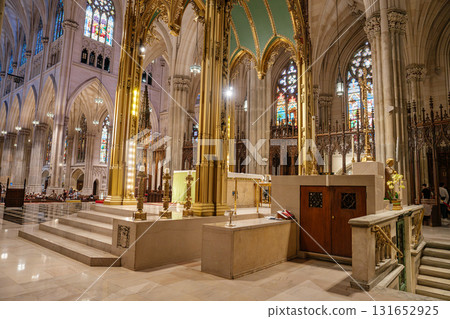 This image showcases the golden altar area and surrounding architecture inside St. Patrick's Cathedral in New York City. Stained glass windows, tall columns, and marble steps highlight the grandeur of This image showcases the golden altar area and surrounding architecture inside St. Patrick's Cathedral in New York City. Stained glass windows, tall columns, and marble steps highlight the grandeur of 131652925