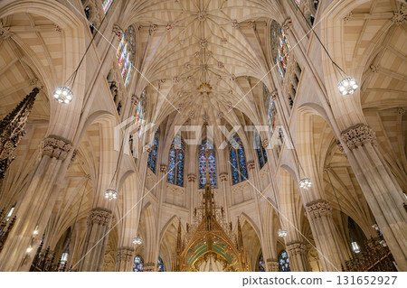 This image captures the soaring vaulted ceiling and intricate stained glass windows above the altar of St. Patrick's Cathedral in New York City. The stunning Gothic architecture is enriched with 131652927