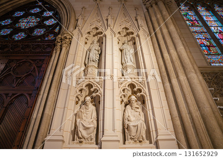 The image displays detailed stone statues of saints, including St. Gregory Nazianzen and St. Athanasius, inside St. Patrick's Cathedral in New York City. Surrounding Gothic architecture includes 131652929