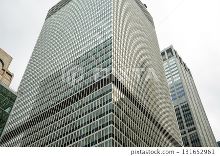 A massive glass skyscraper in New York City displays a precise geometric grid of windows. The building's reflective surface and clean lines represent classic corporate architecture. 131652961
