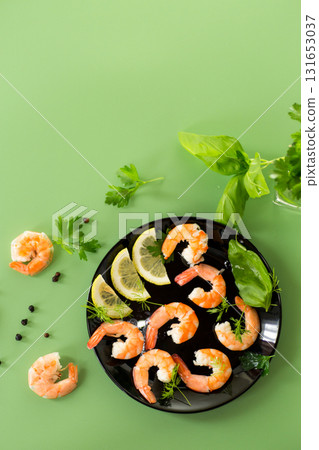 Close-up of boiled shrimps with lemon slices, isolated on green background 131653037