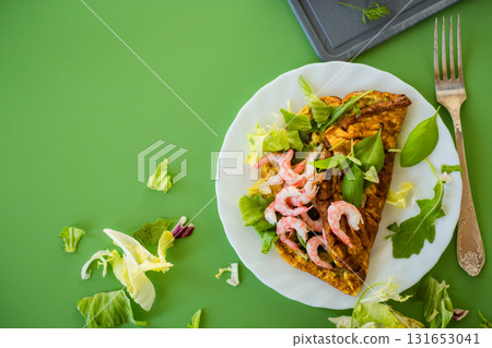 Fried omelette with shrimps and greens on a green background Fried omelette with shrimps and greens on a green background 131653041
