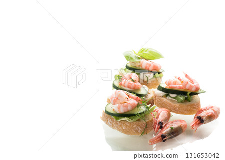 Minimalistic canapes with shrimps, salad and cucumber on a white background 131653042