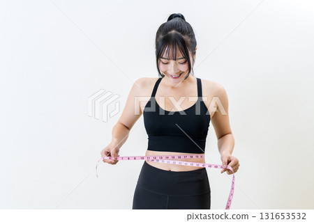 Woman measuring her waist with a tape measure. A cool woman working out. Diet. White background. 131653532
