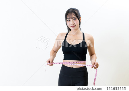 Woman measuring her waist with a tape measure. A cool woman working out. Diet. White background. 131653535