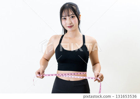 Woman measuring her waist with a tape measure. A cool woman working out. Diet. White background. Trimmed. Woman measuring her waist with a tape measure. A cool woman working out. Diet. White background. Trimmed. 131653536