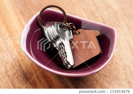 Set of hotel room keys with house keychain in ceramic bowl on wooden table 131653676