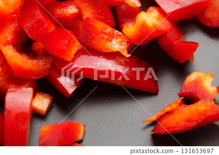 Pieces of chopped fresh red bell pepper on black ceramic. Organic vegetable salad ingredient. Macro shot.  131653697