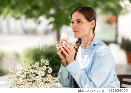 Icecream Woman Daisies Joy: Girl holds dessert beside flowers during summer at outdoor table. Icecream Woman Daisies Joy: Girl holds dessert beside flowers during summer at outdoor table. 131654015