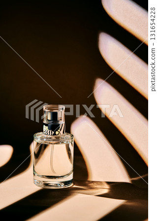 Is the perfume spray bottle lying on a beige background with shadow stripes. 131654228