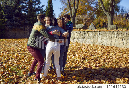group of a young happy smiling friends walking in the autumn park and hugging. group of a young happy smiling friends walking in the autumn park and hugging. 131654380