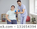 Physiotherapist helping overweight woman patient during muscle rehabilitation physiotherapy 131654394