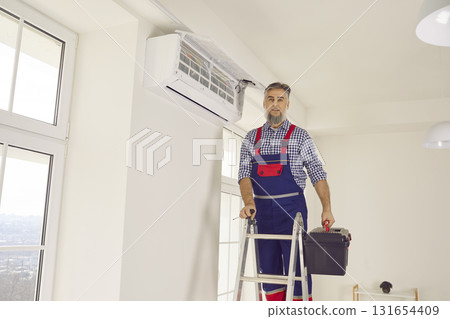 Portrait of electrician with screwdriver looking at camera and smiling maintaining air conditioner Portrait of electrician with screwdriver looking at camera and smiling maintaining air conditioner 131654409