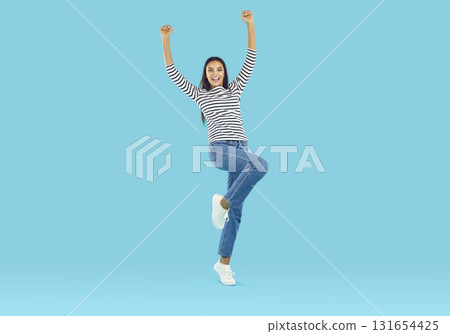 Optimistic woman standing on one leg with her hands raised Optimistic woman standing on one leg with her hands raised 131654425