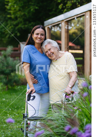 Home nurse spending time with elderly lady patient in garden. 131655117