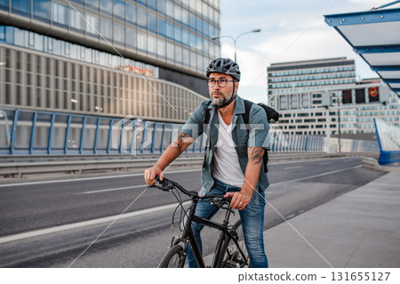 Urban commuter cycling on street carrying backpack. 131655127