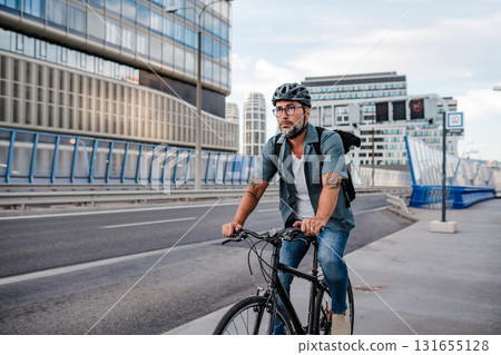Urban commuter cycling on street carrying backpack. 131655128
