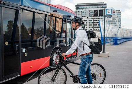 Cyclist boarding city bus with bicycle. 131655132