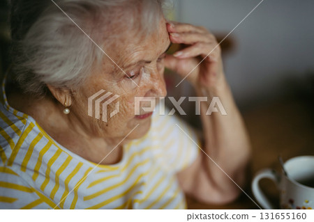 Portrait of worried senior woman crying in kitchen. 131655160