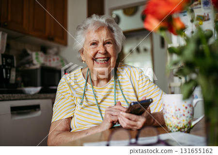 Portrait of senior woman holding smartphone at home. 131655162