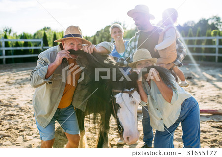 Joyful child sitting in wheelbarrow, family portrait on farm. 131655177