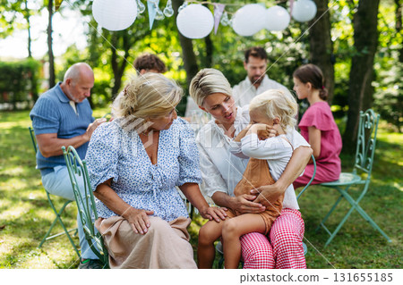 Smiling grandmother talking with her daughter, holding grandchild, family gathering. Smiling grandmother talking with her daughter, holding grandchild, family gathering. 131655185