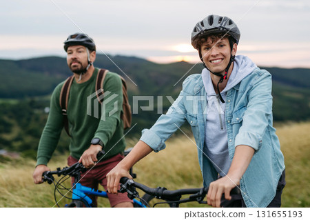 Dad and teen boy riding bicycles in mountains. Cycling trip during autumn day. 131655193