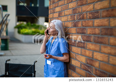 Older nurse resting during long hospital shift, making phone call Older nurse resting during long hospital shift, making phone call 131655243